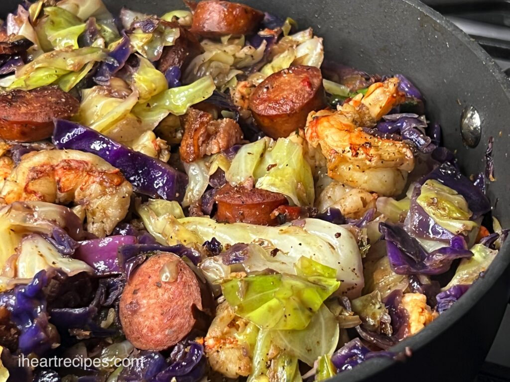 A skillet filled with seasoned fried cabbage, cooked with shrimp and sausage.