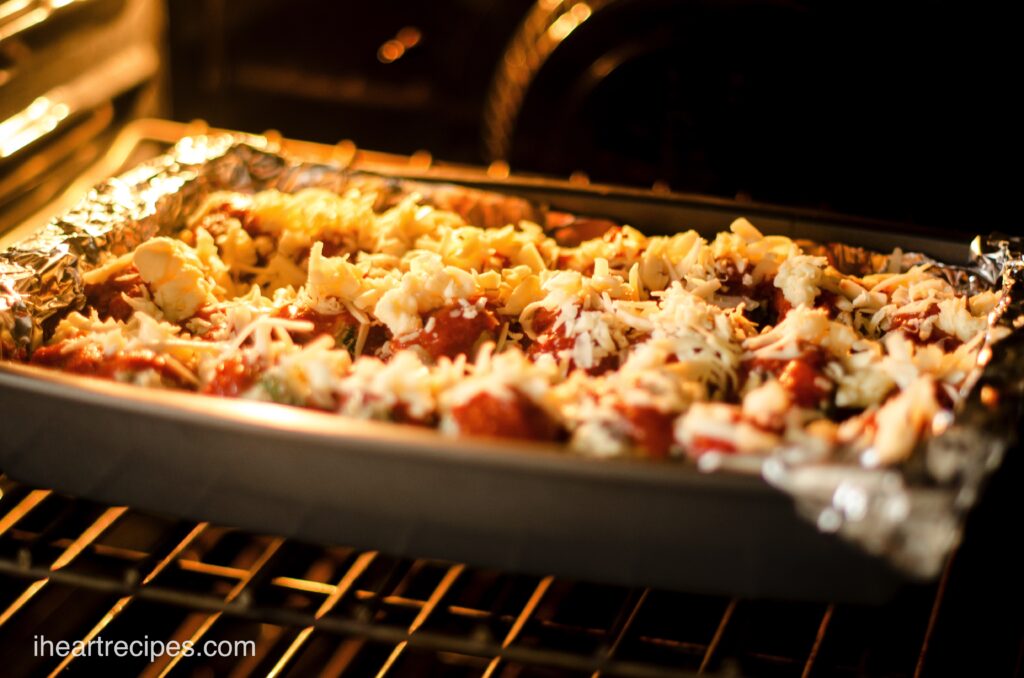 A pan of homemade Italian stuffed shells baking in the oven, topped with shredded cheese.