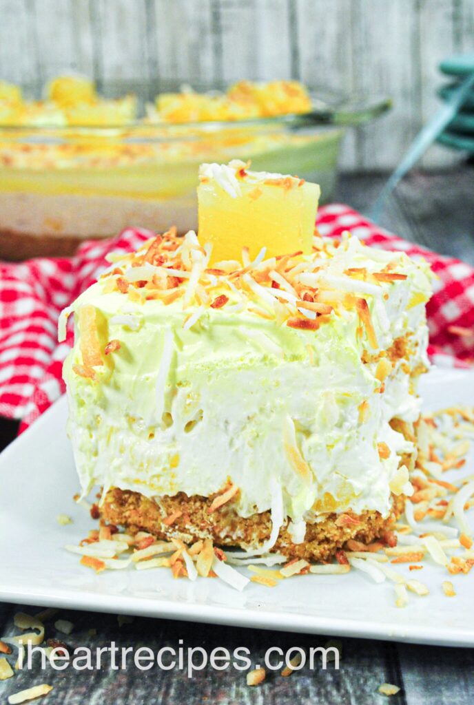 A single slice of creamy no-bake pina colada cheesecake served on a plate, topped with pineapple and toasted coconut.