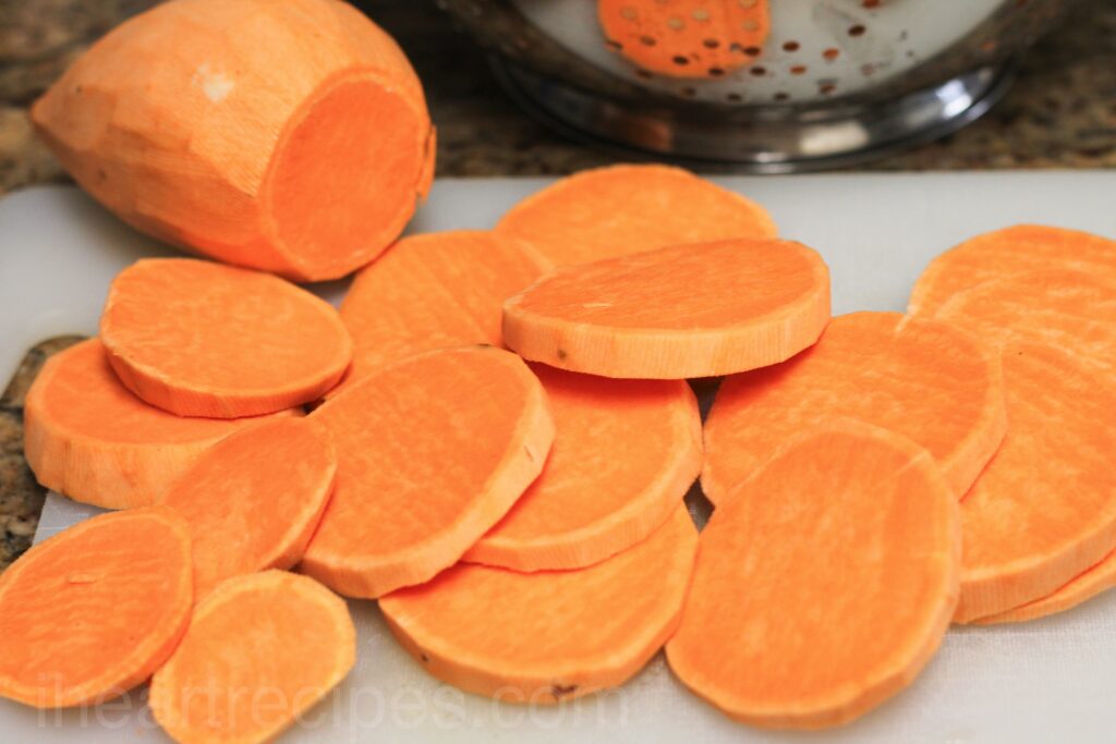 peeled and sliced yams on a white chopping board.