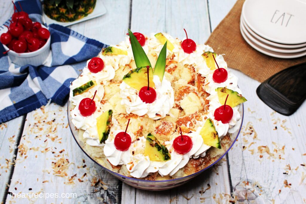 An overhead image of a Pina Colada Cake Trifle, topped with dollops of whipped cream, cherries, and pineapple slices.