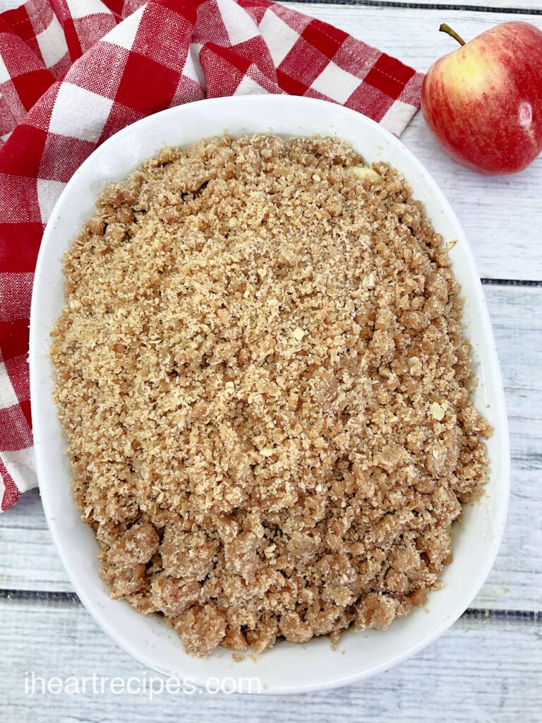 An overhead image of a homemade apple crip in a white baking dish, topped with a streusel topping.