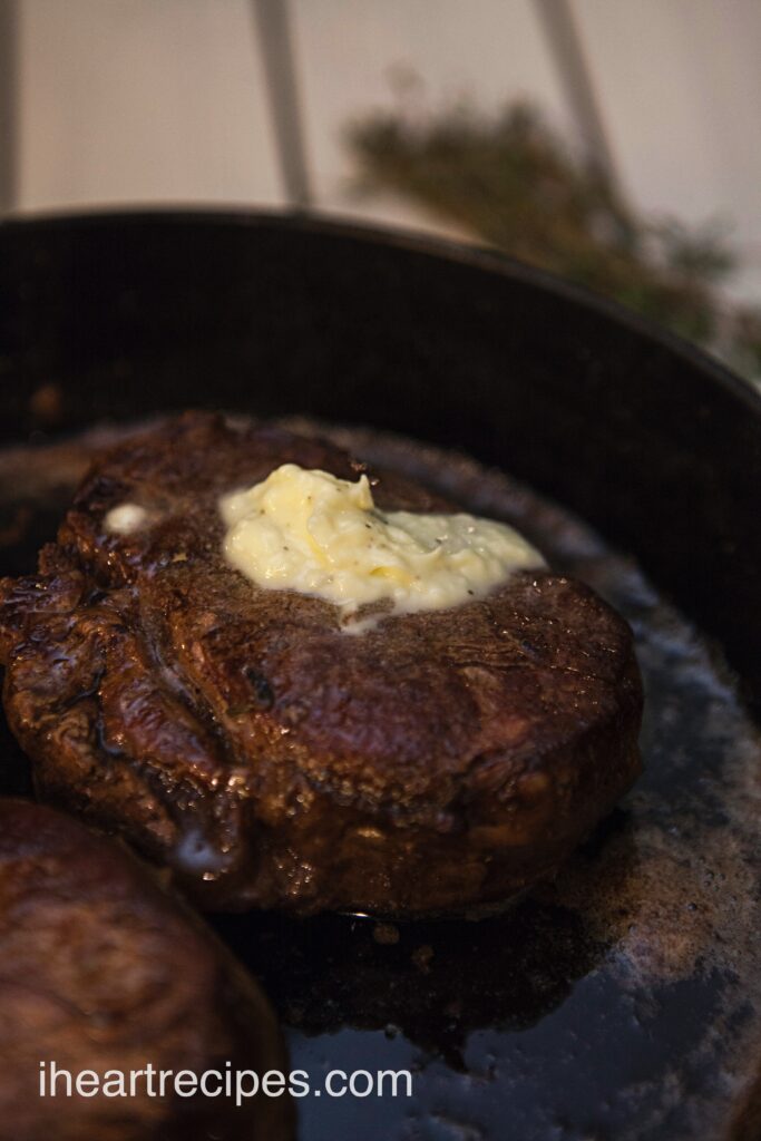 Filet mignon with herb butter mushrooms in a cast iron skillet. 