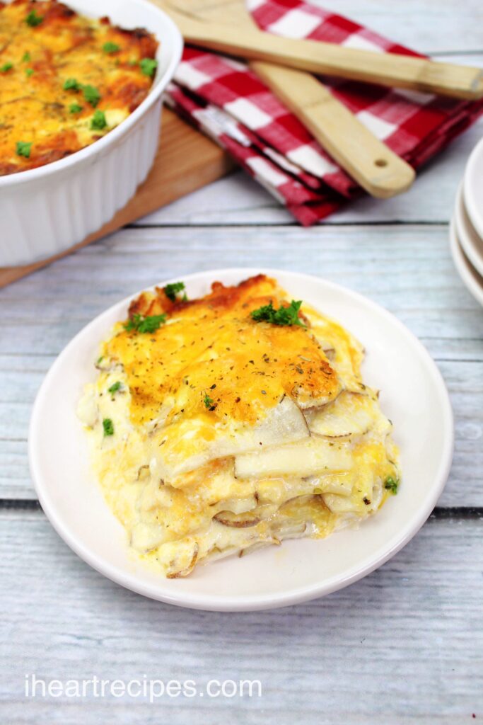 A serving of creamy and golden simple scalloped potatoes on a round white plate. 