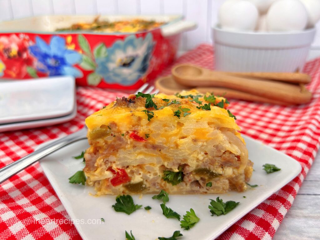 A single slice of cheesy hash brown casserole served on a white plate, garnished with fresh parsley.