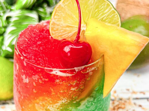 A red, yellow, and green slushy margarita served in a glass.