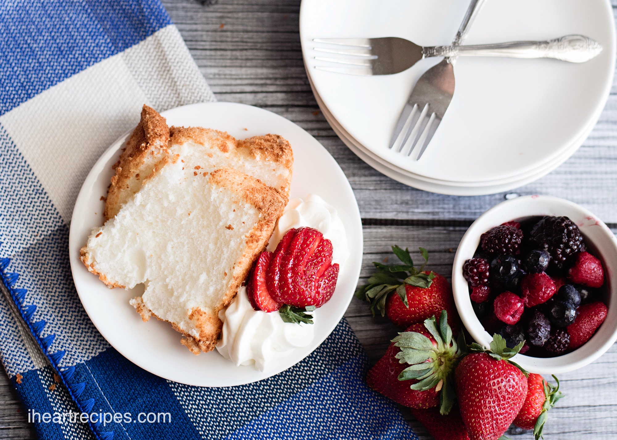 Slices of homemade angel food cake served with fresh berries and whipped cream.
