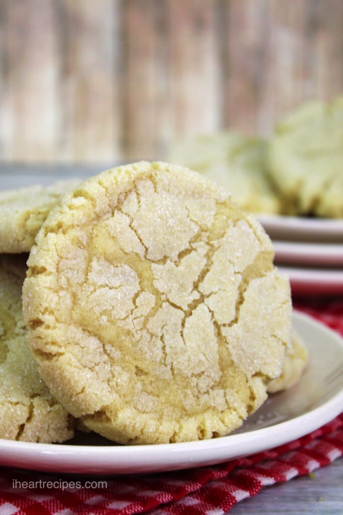 A stack of golden traditional sugar cookies on a round white plate set on a red and white checkered cloth.