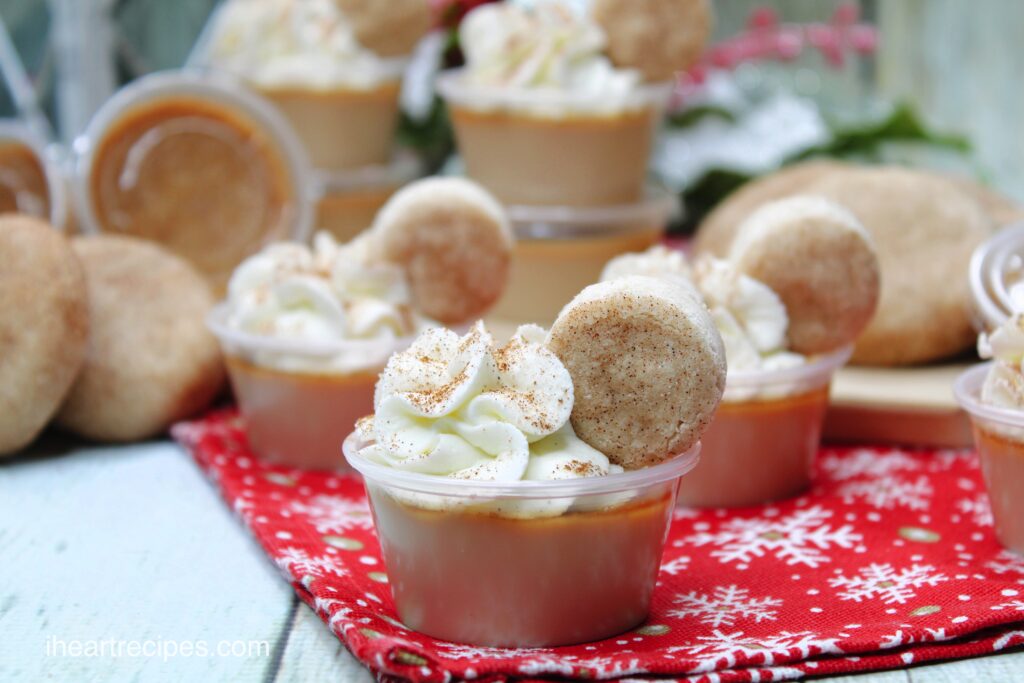 Stacks and rows of single serve Snickerdoodle Jello Shots on a red and white snowflake tablecloth.