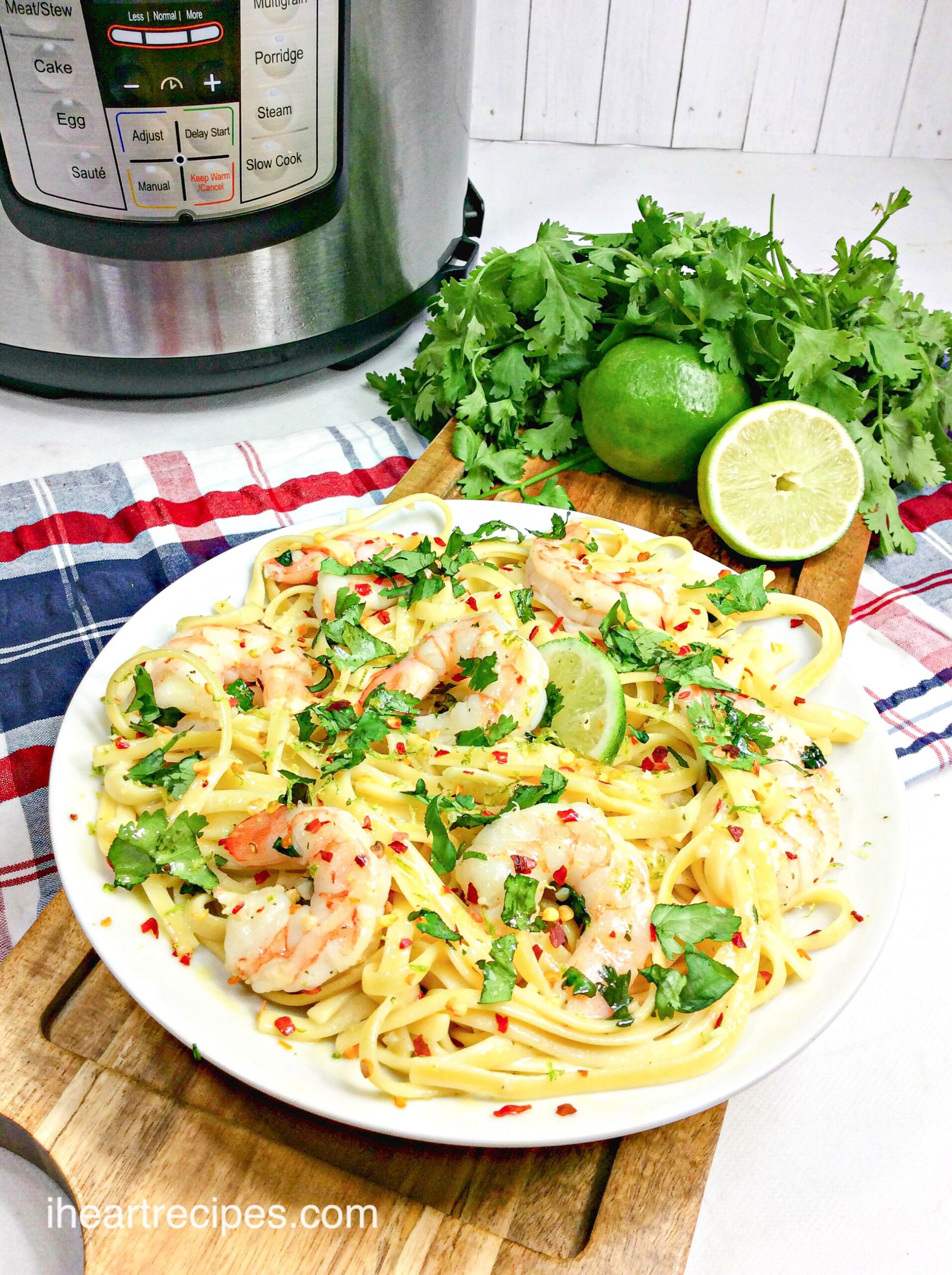 A large plate filled with Instant Pot shrimp scampi -- tender creamy pasta and cooked shrimp, garnished with parsley and lime, cooked in the Instant Pot for a quick and delicious dinner.