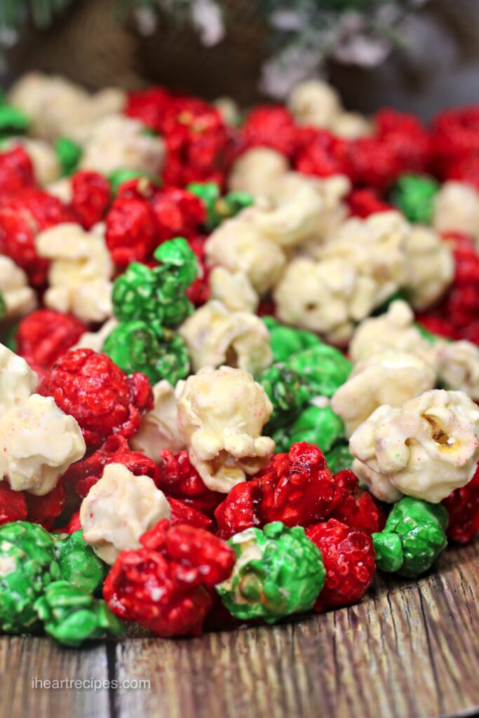 Sweet and colorful Christmas popcorn is served on a wooden platter. 