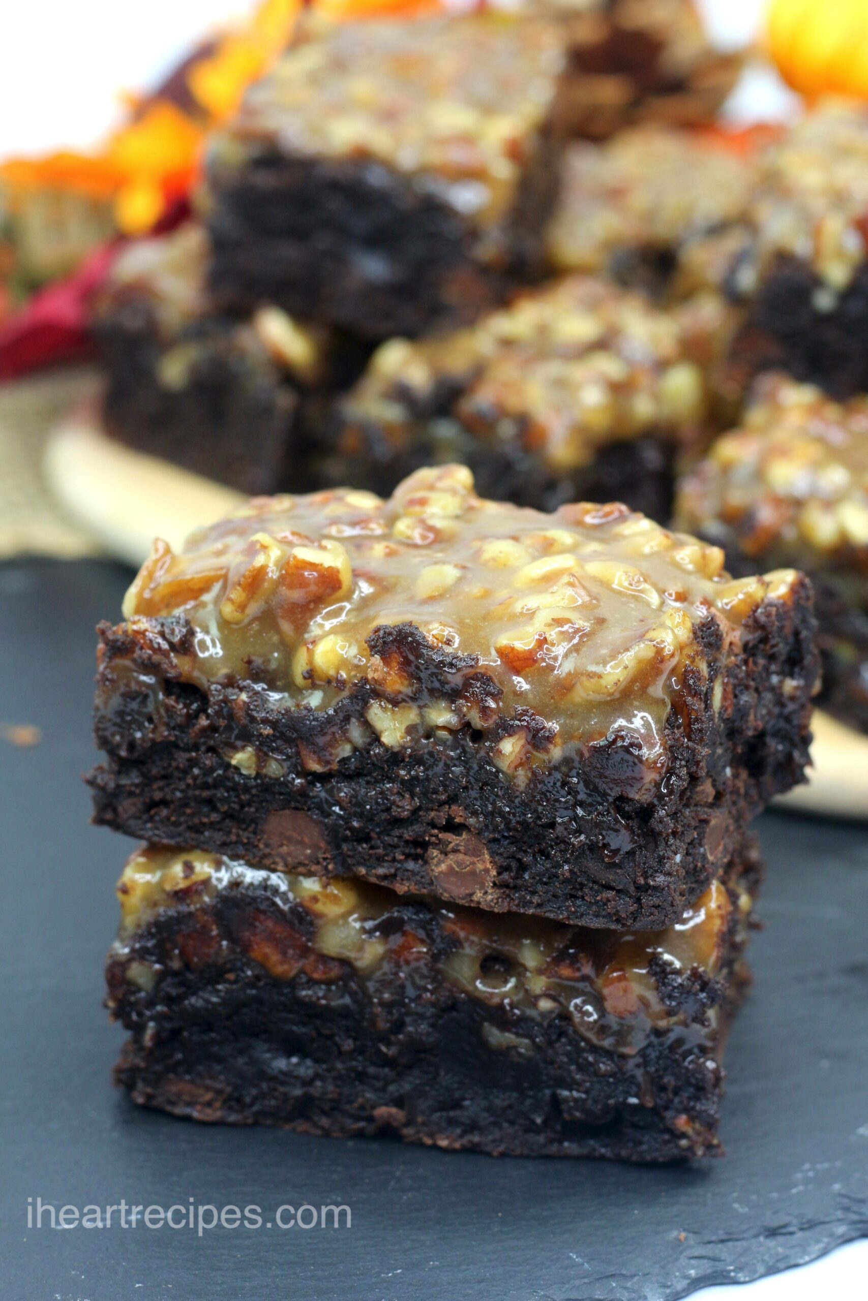Two fudgy pecan pie brownies stacked on top of each other. These sweet, moist brownies have chocolate chips in each bite, along with a gooey pecan pie filling.