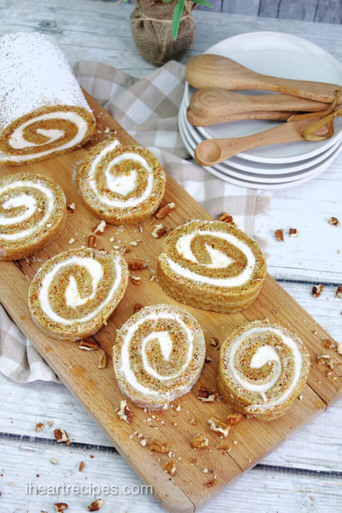 Slices of Rolled Carrot Cake are spread out on a wooden platter. 