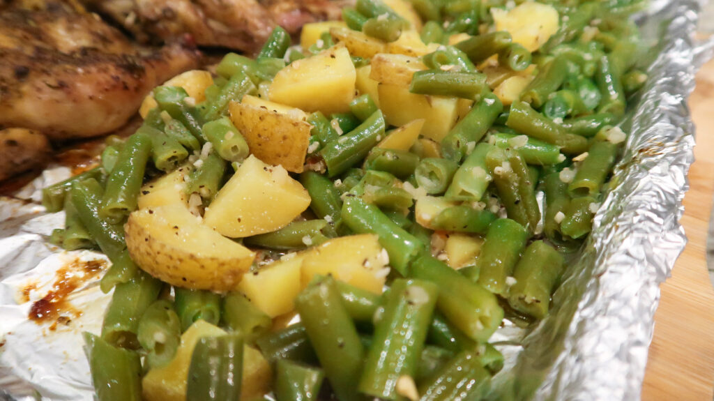 A close up of bright green beans mixed with golden potatoes. 