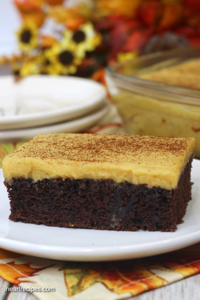 A close up shot of dense chocolate cake spread with creamy pumpkin frosting. 