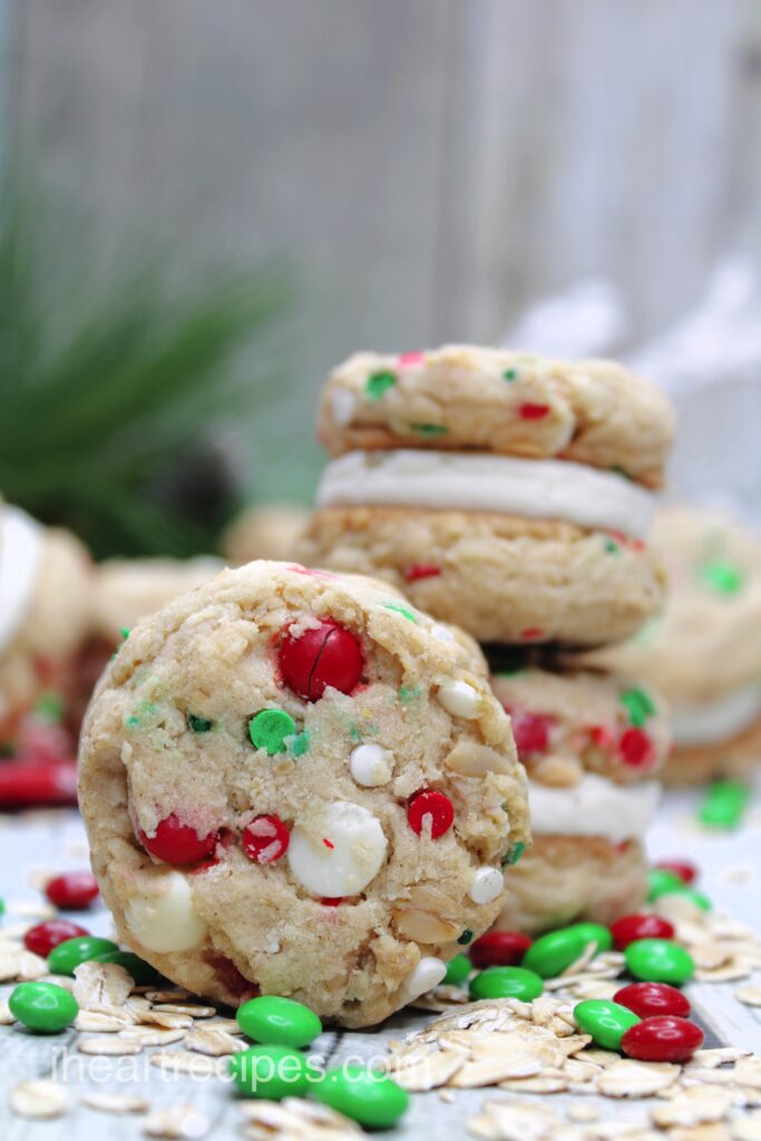 A close-up of Christmas Oatmeal Cookie Sandwiches dotted with festive candies and chewy oats. 