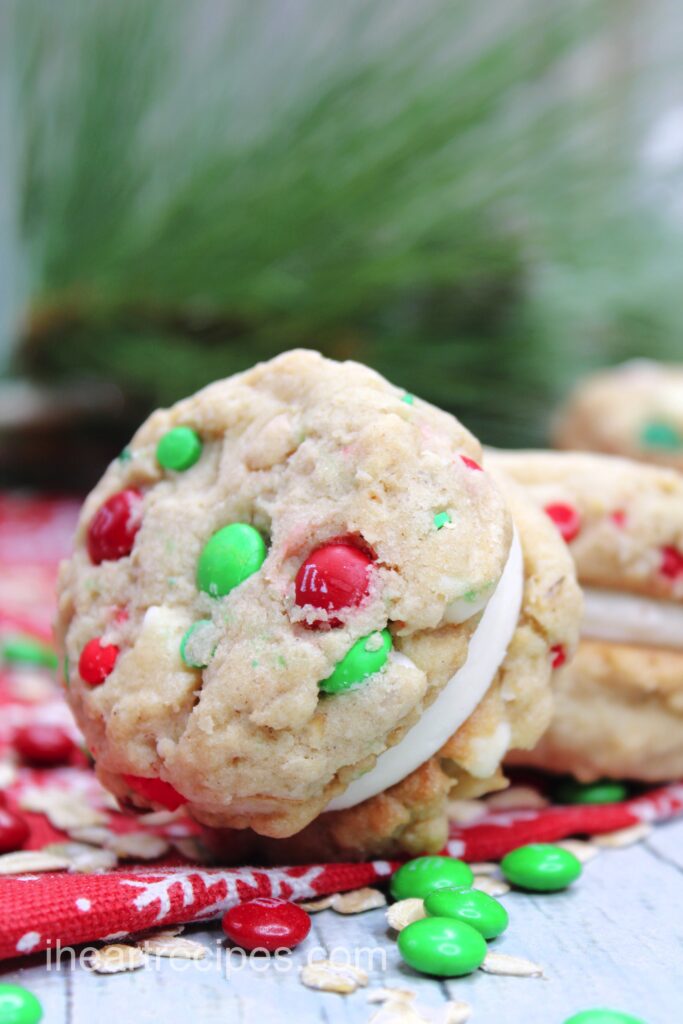 Christmas Oatmeal Cookie Sandwiches laying on a festive placemat sprinkled with red and green M&M's. 