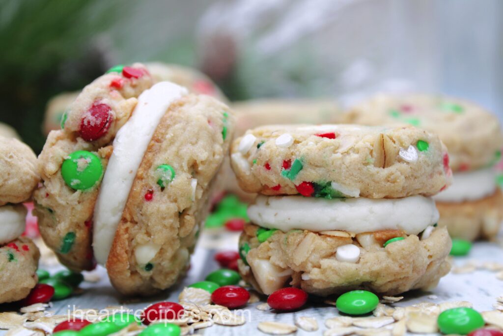 A sideview of Christmas Oatmeal Cookie Sandwiches showing a creamy vanilla filling and festive candies throughout. 