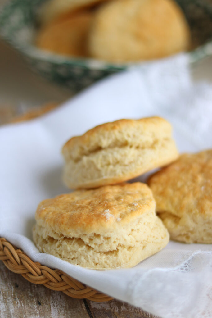 Layered golden buttermilk biscuits resting on a white cloth.   