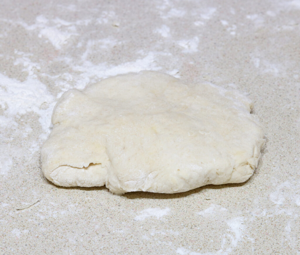 Buttermilk biscuit dough resting on a floured surface. 