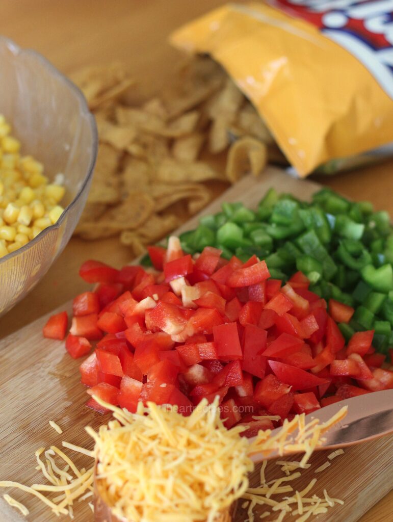 All the ingredients to make Easy Frito Salad are arranged on a table. 