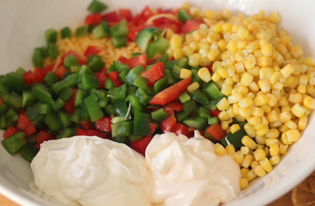 The separated ingredients to make Easy Frito Salad fill a white mixing bowl.  