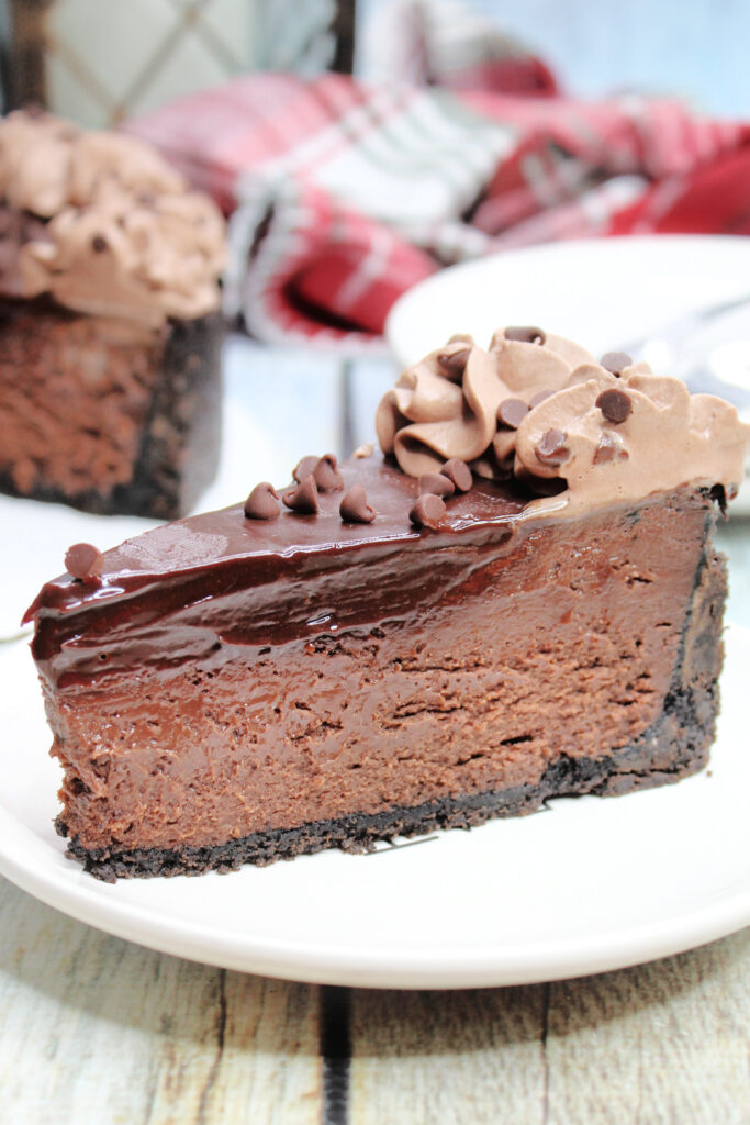 A slice of chocolate cheesecake on a white plate. Layers of various shades and densities of chocolate are seen.