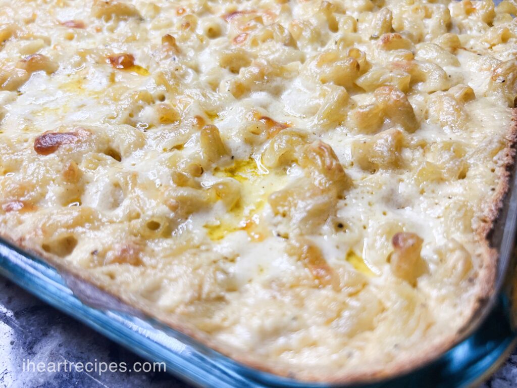 A closeup of creamy and gooey macaroni and cheese in a glass casserole dish.
