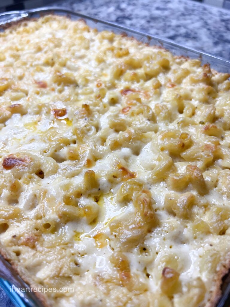 Golden pasta and creamy cheese fill a glass bake dish. 