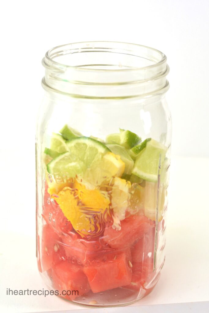 A mason jar filled with cubed watermelon, lime and lemon.