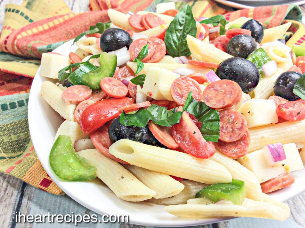 Pizza Pasta Salad pile high in a white pasta bowl. 