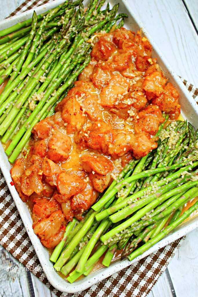 Italian Lemon Chicken and bright green asparagus on a sheet pan ready to be cooked.