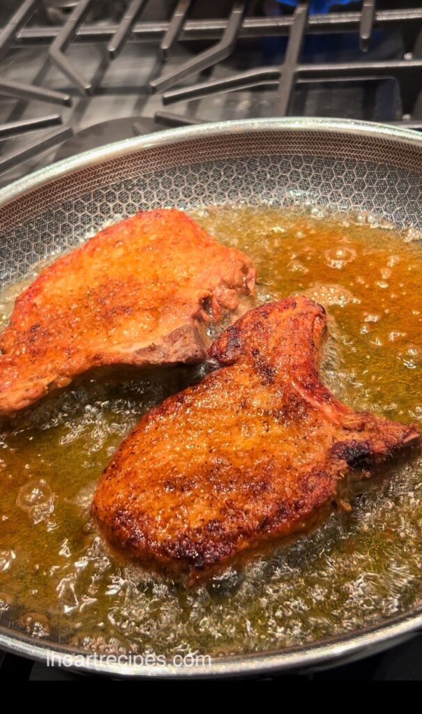Golden Southern Fried Pork Chops in a pan of hot oil. 