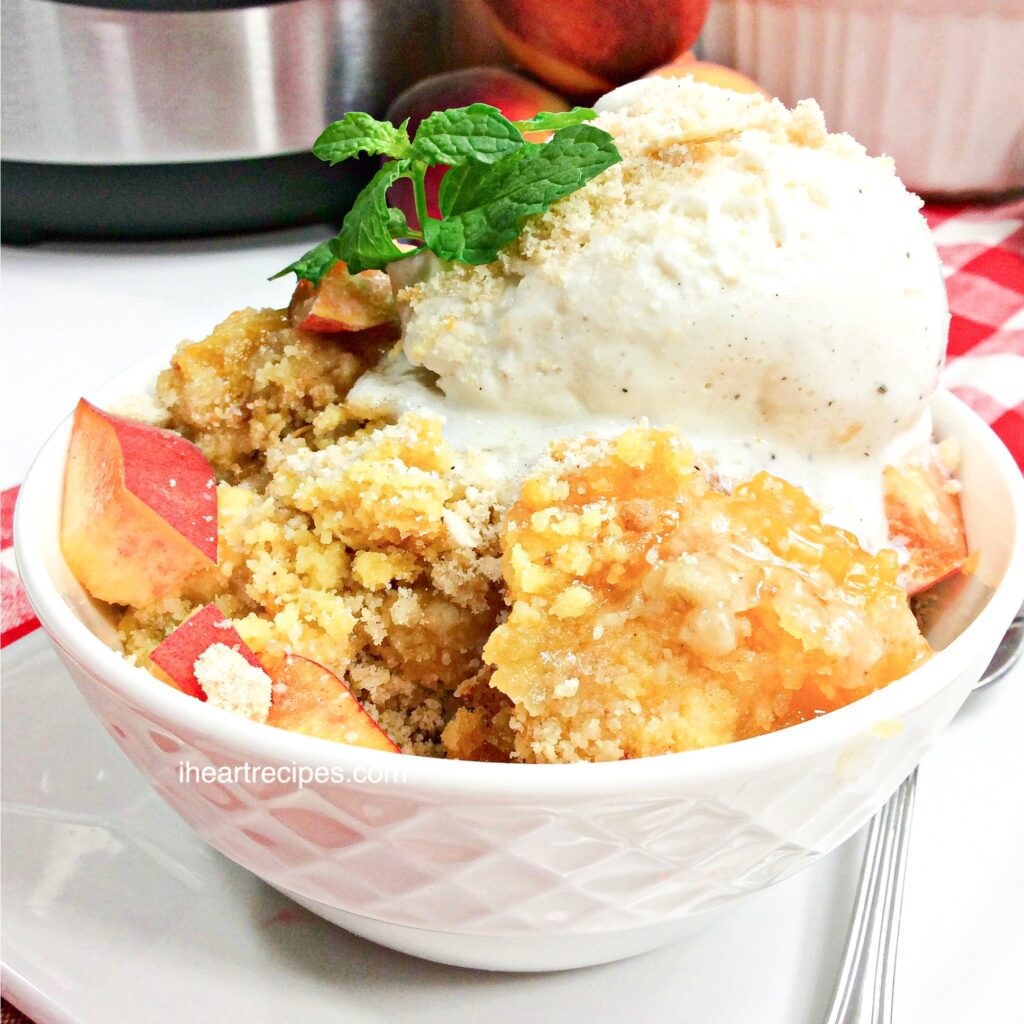 A bowl of moist, buttery peach dump cake topped with vanilla ice cream and a sprig of mint. 