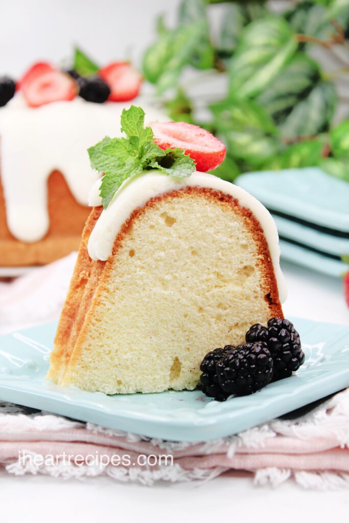 A single serving of Sweet White Wine Pound Cake on a light blue plate garnished with juicy blackberries. 