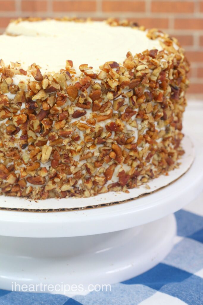 A close up image of three layer carrot cake showcasing the pecan piece coating.  