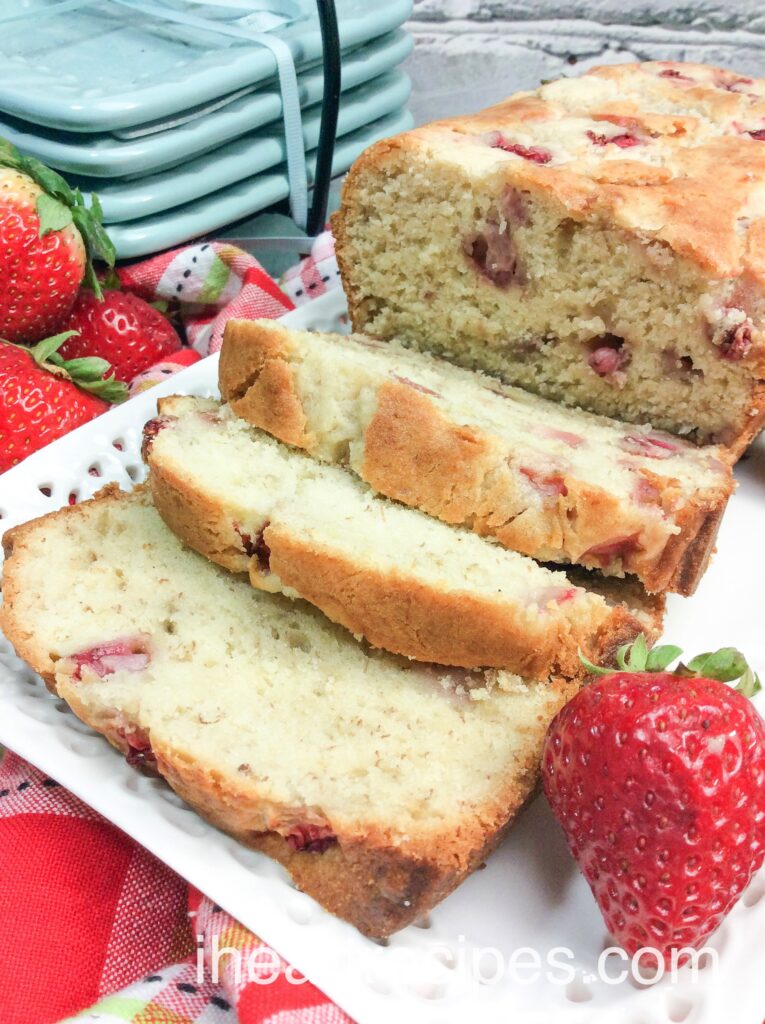 A close up image of sliced strawberries and cream bread showcasing a moist loaf with dots of strawberries pieces.  