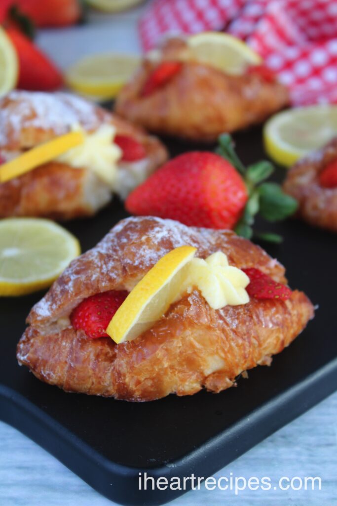 A flaky, golden croissant stuffed with lemon custard, sliced strawberries and a lemon wedge. 
