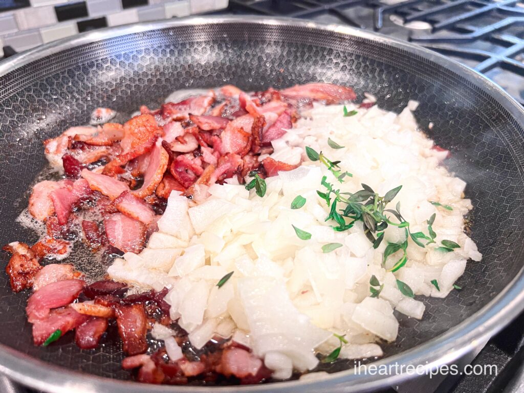 Diced onions, bits of bacon and fresh herbs sizzle in a frying pan. 