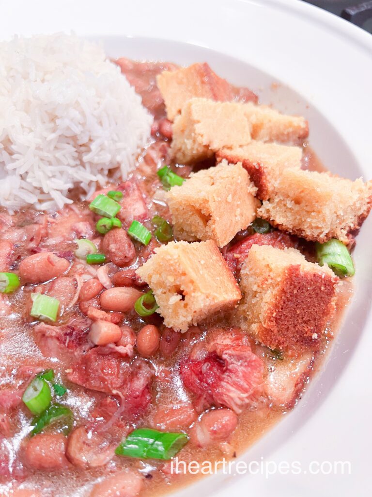 Golden cornbread cubes, tender white rice and savory southern pinto beans fill a white bowl. 