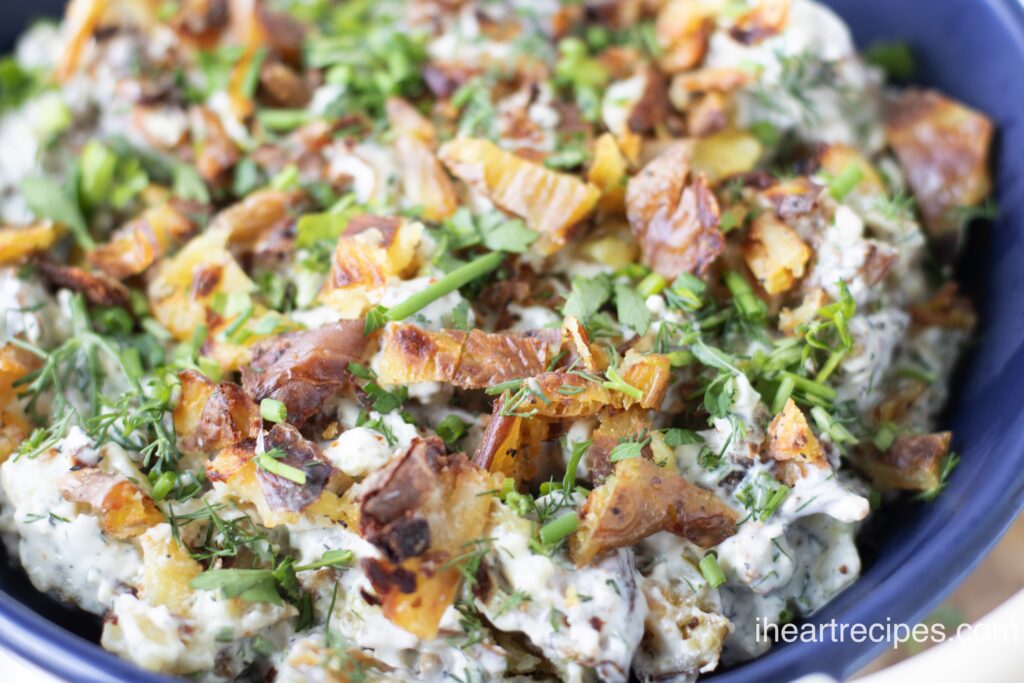 Crunchy and creamy potato salad heaped into a blue bowl. 