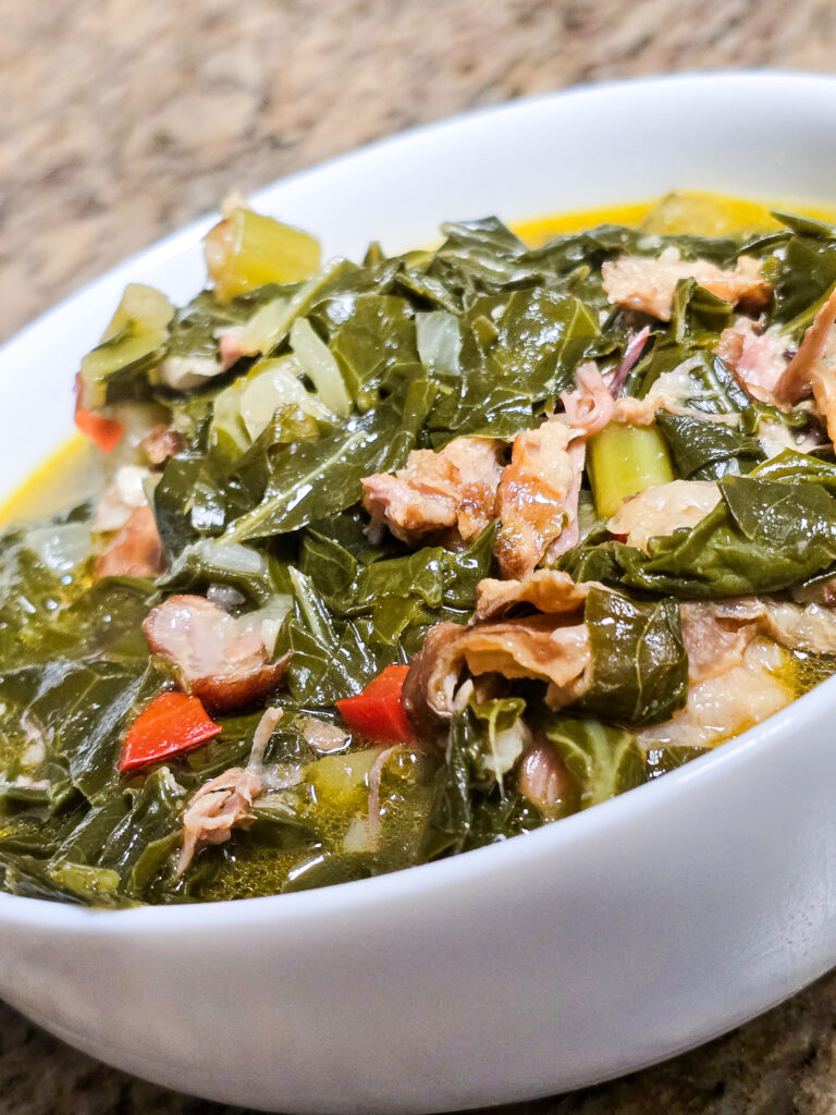 Southern style collard greens with smoked turkey in a white bowl.