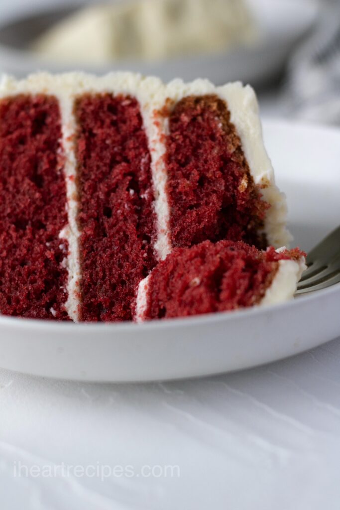 Slice of cake with cream cheese frosting on a plate.